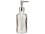 En pumpeflaske af klart glas med en sølvfarvet metaldispenser, der står oprejst på en hvid baggrund.
