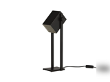 En moderne sort bordlampe med en geometrisk, rektangulær lampeskærm og et lysdæksel med gittermønster, der står på en flad fod med synlig strømledning og afbryder.