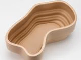 En beige, nyreformet keramikskål med glatte, lagdelte riller langs de indvendige sider på en hvid baggrund.
