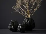 Tre sorte vaser med et bølget tekstureret design står på en mørk overflade; en vase indeholder tørre, beige grene mod en mørk baggrund.