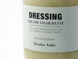 Et nærbillede af en flaske med cremet vinaigrette-dressing mærket DRESSING af Nicolas Vahé med en tekst, der angiver, at den er klar til brug i salater.