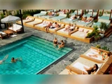 Folk slapper af i liggestole og liggestole omkring en swimmingpool, nogle soler sig, og andre sidder ved poolen i et solrigt, moderne udendørs miljø.