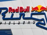 Red Bull-logo over en stiliseret blå racerbane med ordet "Spielberg" nedenunder, vist på en hvid væg.