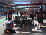 Red Bull Racings Formel 1-team udfører et pitstop på en racerbil i pitlane, hvor besætningsmedlemmer arbejder på dæk og udstyr.