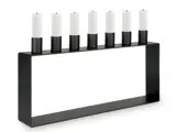 En rektangulær sort lysestage med seks hvide kertelys arrangeret i en række langs den øverste kant.