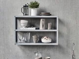 En grå væghylde med tallerkener, glas, skåle, en potteplante og en bog med titlen POLPO, der står pænt opstillet mod en grå væg med struktur over en køkkenbordplade.