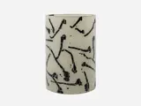 En cylindrisk beige vase med mosaikstruktur og abstrakte sorte penselstrøgsmønstre spredt ud over overfladen.