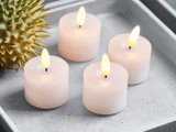 Fire små, hvide LED-stearinlys uden flamme er tændt på et gråt fad ved siden af et pigget, grønt dekorationsobjekt.