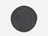 En rund, mørkegrå vævet dækkeserviet med flettet tekstur på en almindelig hvid baggrund.