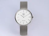 Et minimalistisk sølvfarvet armbåndsur med hvid urskive, tynde timemarkeringer, mesh-rem og safirglas på skiven.
