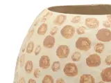 Nærbillede af en beige keramikpotte med brune cirkulære pletter i forskellige størrelser på en hvid baggrund.
