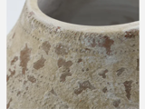 Nærbillede af den strukturerede, forvitrede overflade på en beige keramikvase med brune pletter og ru, ujævne områder nær kanten.