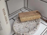 En rektangulær træbørste med naturlige børster hviler på en plettet sæbeskål ved siden af en flaske med påskriften BODY WASH i et flisebelagt badeværelseshjørne.