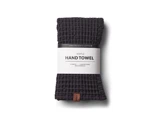 Et mørkegråt håndklæde med vaffelstruktur indpakket i en etiket med teksten 100% Organic Cotton Waffle Hand Towel.