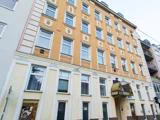 En bygning i flere etager med gule og beige vægge, store vinduer og et skilt med teksten "hotel" over indgangen. Facaden har dekorative arkitektoniske detaljer.
