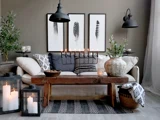 En hyggelig stue med en beige sofa, mønstrede puder, sofabord i træ, stearinlys, potteplanter og sort-hvid fjerkunst på væggen.