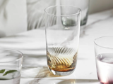 Et næsten tomt glas med en lille mængde brun væske står på en marmorplade omgivet af andre delvist fyldte glas.
