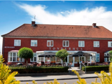 En toetagers rød murstensbygning med rødt tegltag, mærket TØNDERHUS, med udendørs siddepladser under parasoller og et skilt til en restaurant.