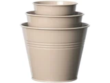 Tre beige metalspande i forskellige størrelser er stablet inden i hinanden, så de danner et indskudt arrangement.