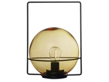 En moderne bordlampe med en rund ravfarvet glasskærm, en synlig pære og et minimalistisk sort, rektangulært metalstel.