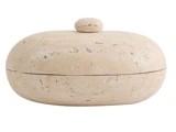 En rund, beige stenbeholder med et matchende låg og en lille knop på toppen, der ligner en glat flodsten.