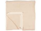 Et foldet, lysbeige, struktureret musselintæppe med et synligt hjørne, der er vendt for at vise indersiden.