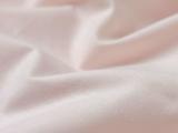 Nærbillede af blødt, lyserødt stof med blide folder og en glat tekstur.