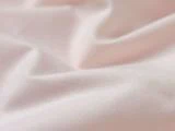 Nærbillede af blødt, lyserødt stof med blide folder og en glat tekstur.
