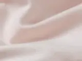 Nærbillede af lyserødt, glat stof med blide folder og blød tekstur.