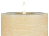 Nærbillede af et beige bloklys med en synlig flamme mod en hvid baggrund.