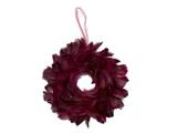 En cirkulær krans af mørke bordeauxfarvede fjer med en lyserød båndstrop til ophængning.