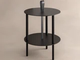 Et moderne sort sidebord med to runde hylder, tre ben og et håndtag med løkke på toppen, sat op mod en neutral baggrund.