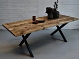 Et træbord med sorte metalben, dækket med en plante i en potte og flere keramiske kopper og tallerkener, placeret indendørs mod en struktureret hvid væg.