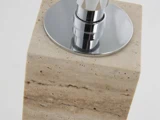 Nærbillede af en sæbedispenser med en beige marmorbund og en skinnende sølvpumpe på toppen mod en hvid baggrund.