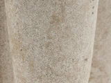 Nærbillede af en struktureret, beige stenoverflade med små porer og naturlige, uregelmæssige mønstre.