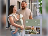 En smilende kvinde holder en sovende baby i en bæresele ved siden af en skægget mand udendørs. Indsatte billeder viser vanddråber på stoffet og bæreselen foldet sammen til en kompakt taske.