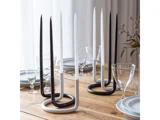 Et spisebord i træ med tallerkener, glas og moderne sort-hvide spiralformede lysestager med høje sort-hvide stearinlys.