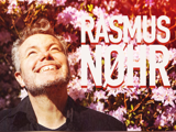 En smilende mand kigger op foran blomstrende pink blomster, med fed tekst RASMUS NØHR ved siden af ham.