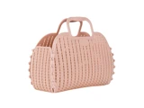 En lyserød håndtaske i vævet stil med afrundede kanter, to hanke og dekorative nitter langs siderne på en hvid baggrund.