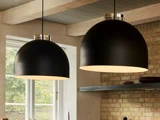 To store, sorte kuppelformede pendler hænger fra loftet i et hyggeligt rum med murstensvægge og et vindue, der lukker naturligt lys ind.