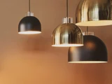 Fire moderne kuppelformede pendler, to sorte og to i metallisk guld, hænger på en varm beige baggrund.