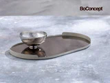 En riflet sølvskål står på en mørk, oval bakke. BoConcept-logoet er i øverste højre hjørne.