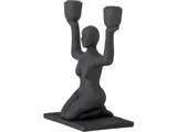 Tekstureret sort skulptur af en knælende menneskeskikkelse, der holder to lysestager højt, en i hver løftet hånd, monteret på en rektangulær base.