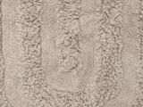 Nærbillede af en beige, struktureret bademåtte med ophøjede, bløde mønstre, der danner et ovalt design på overfladen.