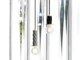 To moderne pendler med armaturer i sort og guld hænger foran et vindue med geometriske paneler i matteret glas.