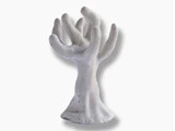 En hvid, spættet keramikskulptur, der ligner en abstrakt hånd med flere fingre, placeret mod en almindelig baggrund.