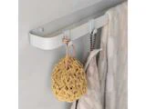 En beige svamp, et stribet håndklæde og et lyst ternet håndklæde hænger på kroge på en moderne hvid væghængt skinne.