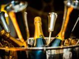 Flasker med Drappier-champagne i en isspand omgivet af metalliske champagnefløjter, klar til fest.