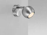 En moderne, vægmonteret sølvfarvet spotlampe med en rund fod og en sfærisk, justerbar lampe, monteret på en ensfarvet lysegrå væg.