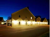 En varmt oplyst, lysegul bygning med navnet Christies Sdr. Hostrup Kro står langs en tom vej i skumringen under en dybblå himmel.